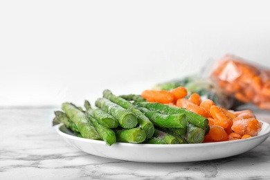 Plate with different frozen vegetables on table