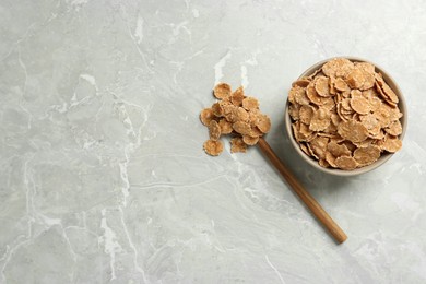 Photo of Ceramic bowl with wheat flakes on grey table, flat lay and space for text. Cooking utensil