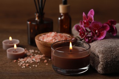 Photo of Beautiful spa composition with burning candles, sea salt and flowers on wooden table