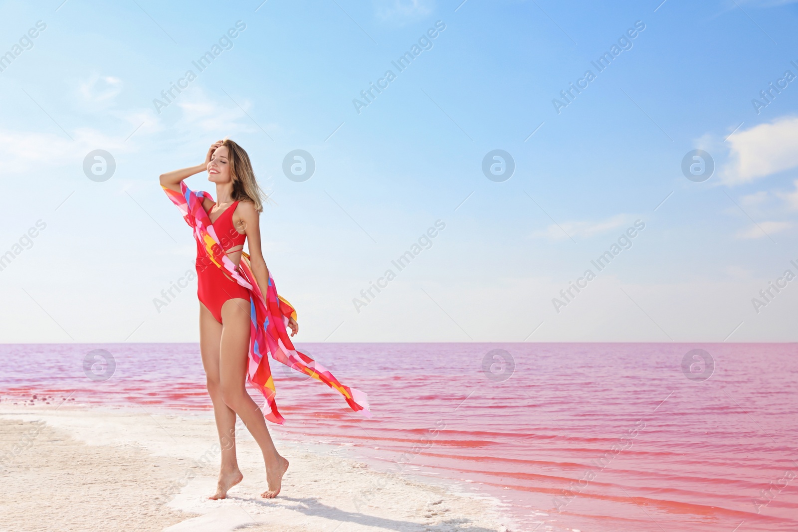 Photo of Beautiful woman in swimsuit posing near pink lake on sunny day