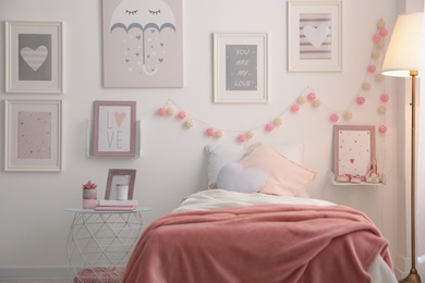 Photo of Stylish child's room interior with beautiful pictures and comfortable bed