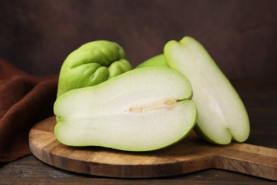 Photo of Cut and whole chayote on wooden table, closeup