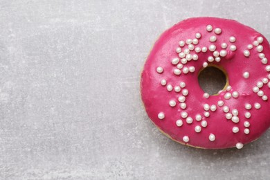 Tasty glazed donut decorated with sprinkles on light grey table, closeup. Space for text