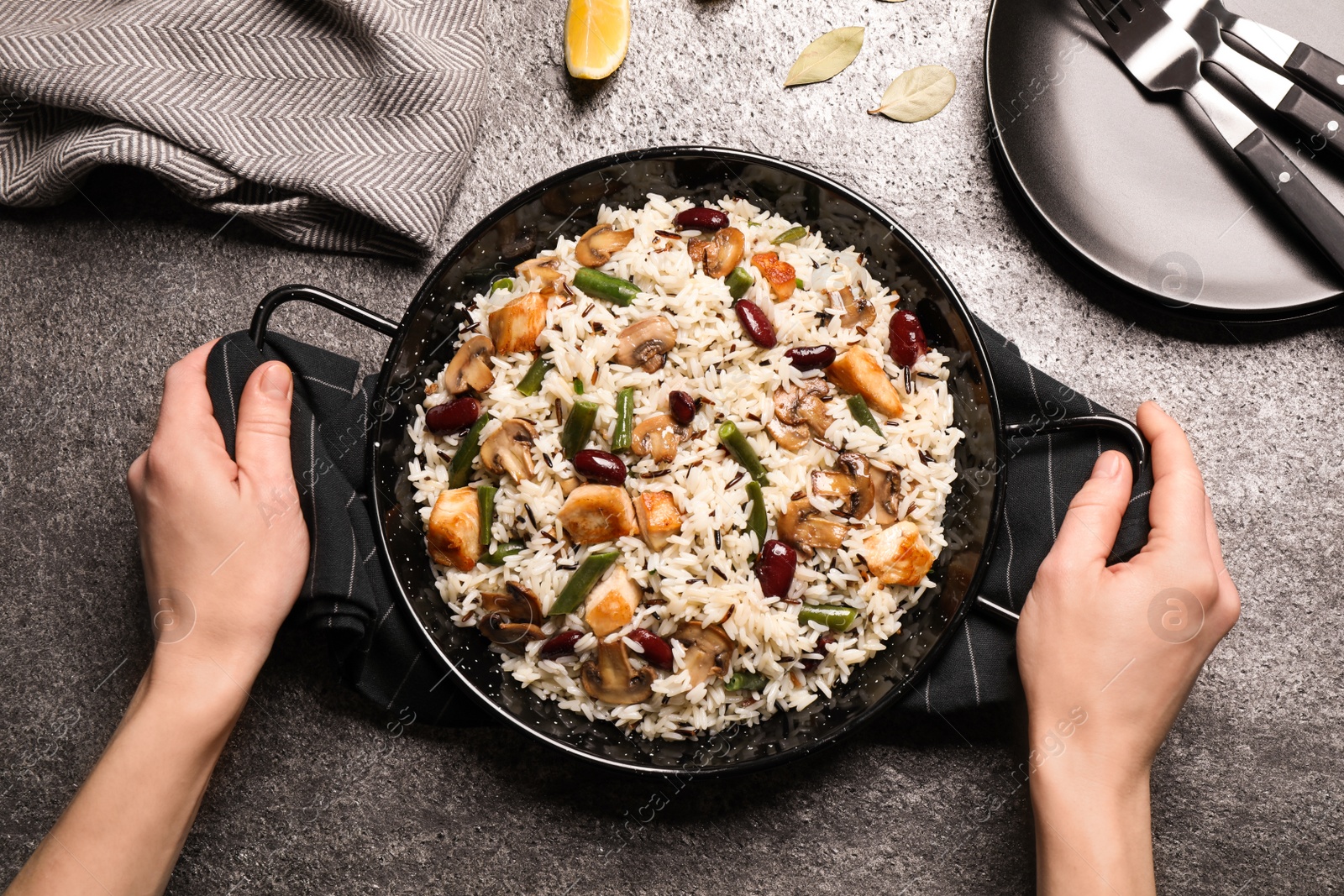 Photo of Woman with delicious rice pilaf at grey table, top view