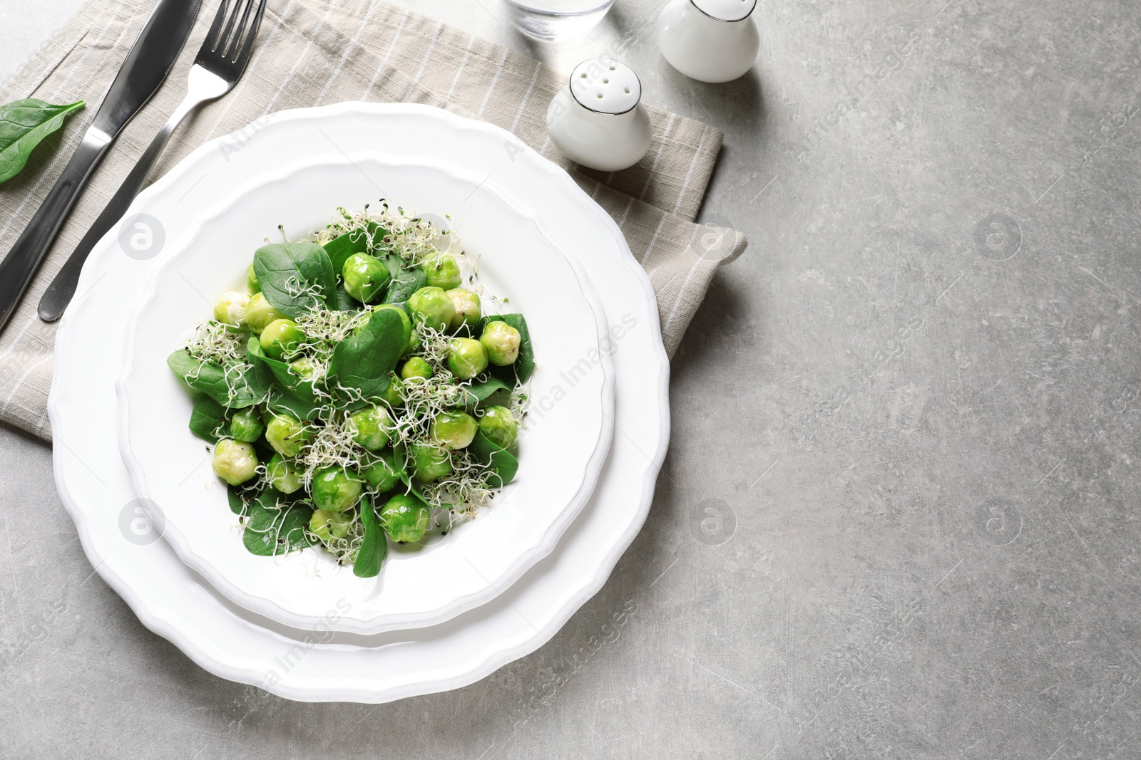 Photo of Plate of delicious salad with Brussels sprouts on grey table, top view. Space for text