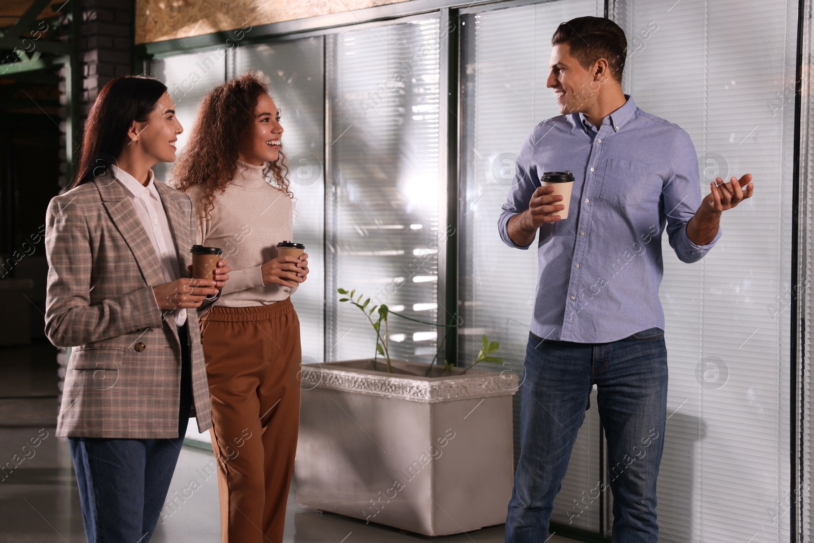 Photo of Group of coworkers talking during coffee break in office