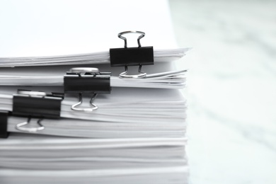 Stack of documents with binder clips on marble table, closeup