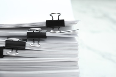 Photo of Stack of documents with binder clips on marble table, closeup