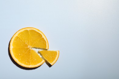 Photo of Slices of juicy orange on light blue background, top view. Space for text