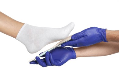 Photo of Orthopedist fitting insole to patient's foot on white background, closeup