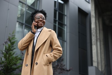 Happy woman talking on smartphone outdoors, space for text. Lawyer, businesswoman, accountant or manager