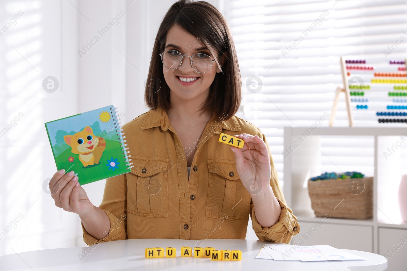 Photo of Happy female English teacher giving lesson indoors. Early childhood education