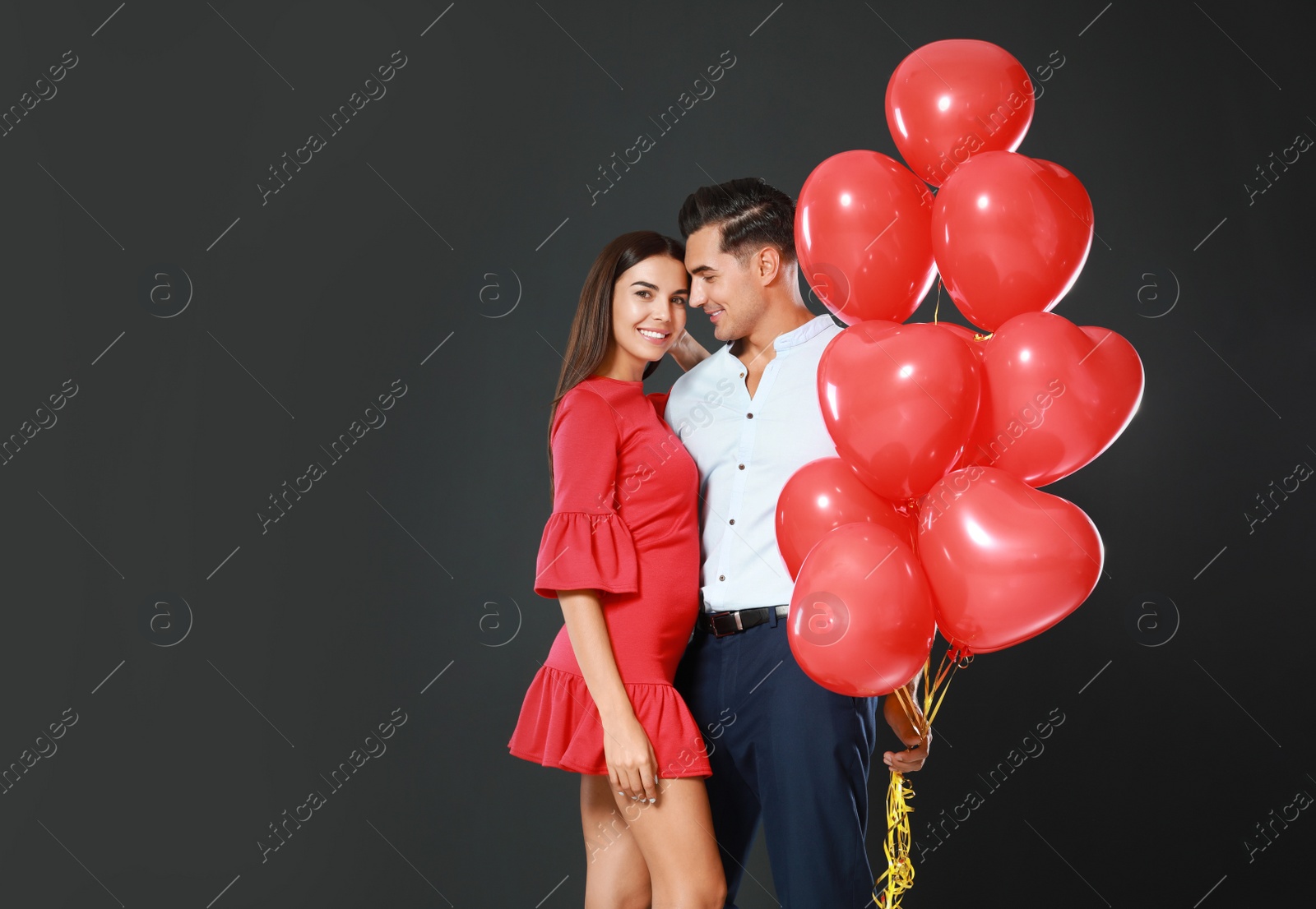 Photo of Beautiful couple with heart shaped balloons on dark background, space for text