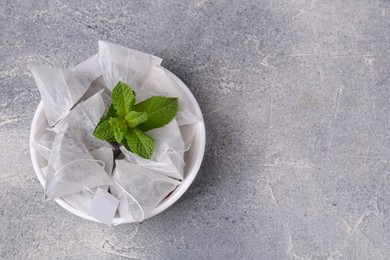 Photo of Tea bags and mint on light grey table, top view. Space for text