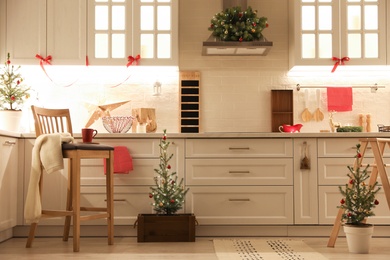 Photo of Small Christmas trees and festive decor in kitchen