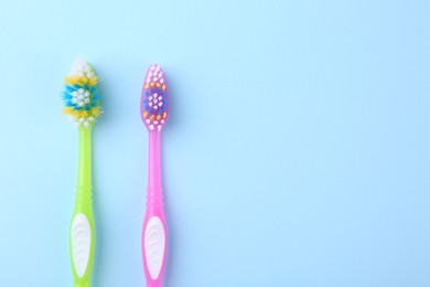 Photo of Colorful plastic toothbrushes on light blue background, flat lay. Space for text