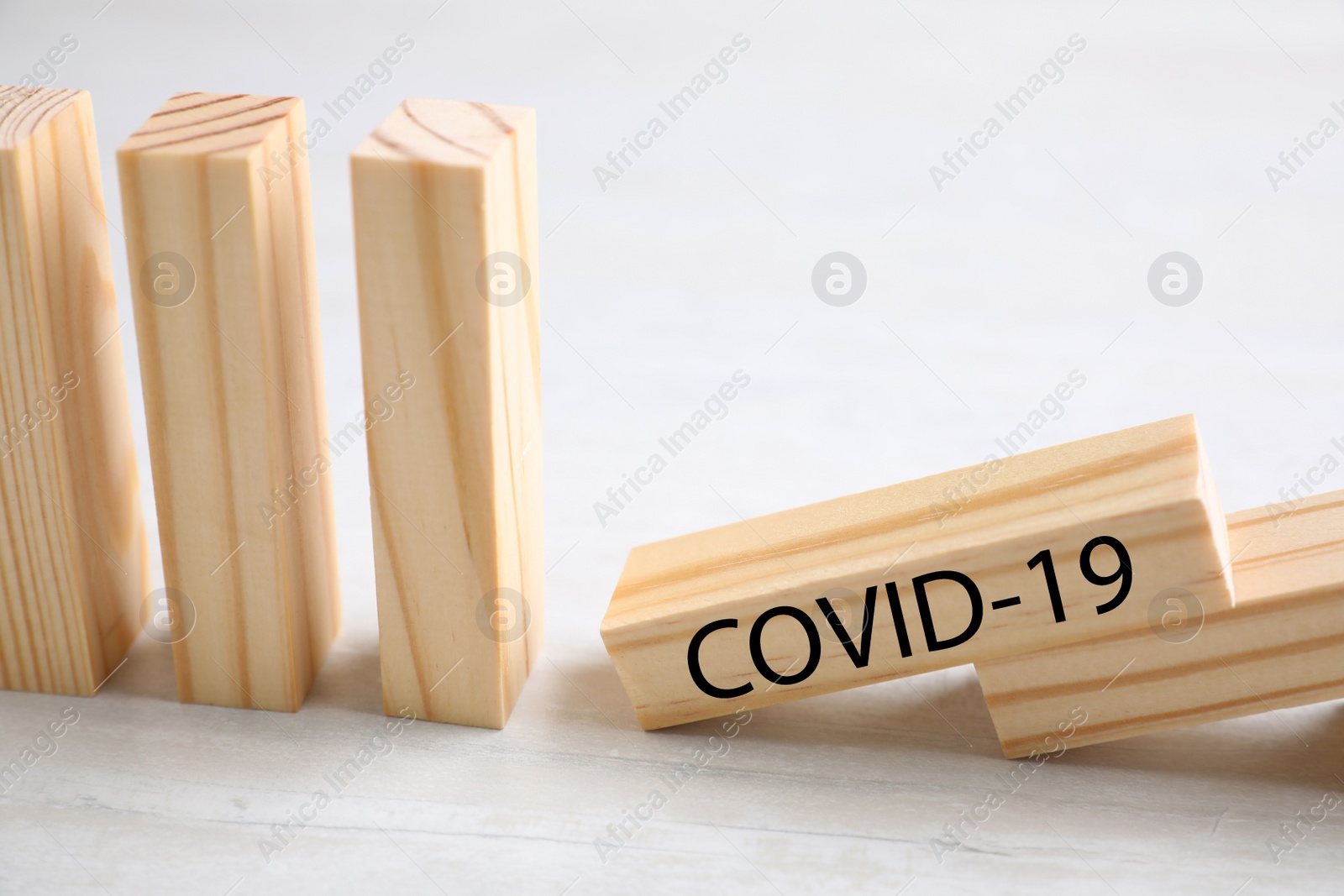 Photo of Wooden domino tiles on white table, closeup. Spreading of coronavirus concept