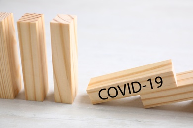 Wooden domino tiles on white table, closeup. Spreading of coronavirus concept