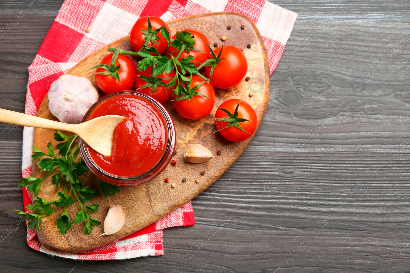 Photo of Tasty ketchup, fresh tomatoes, parsley and spices on grey wooden table, flat lay. Space for text