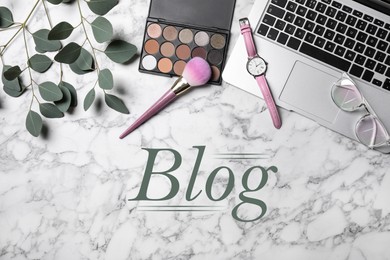 Image of Blogger's workplace with laptop and makeup products on white marble background, flat lay