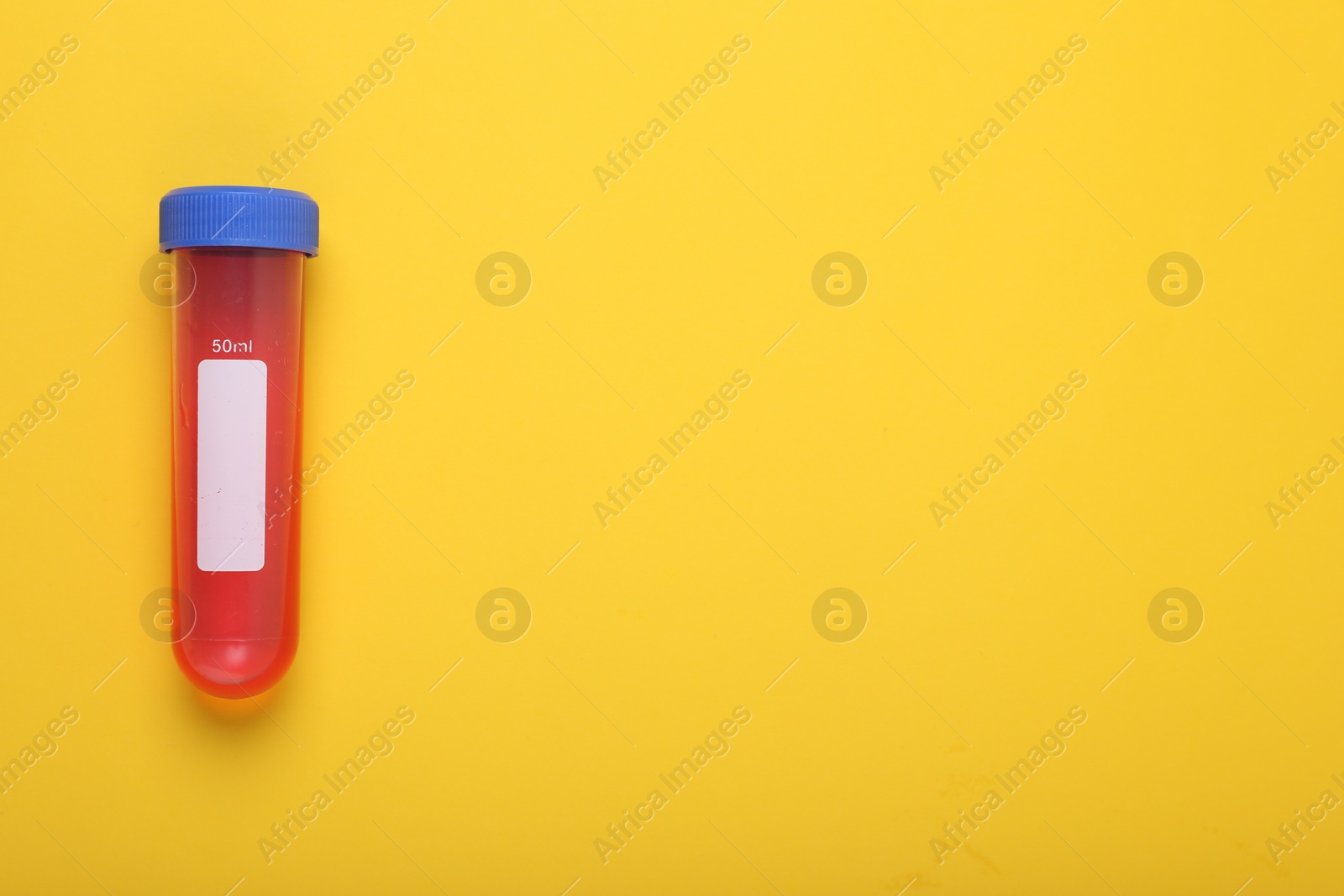 Photo of Test tube with liquid on yellow background, top view and space for text. Kids chemical experiment toy