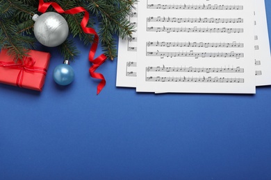 Flat lay composition with Christmas music sheets on blue background, space for text