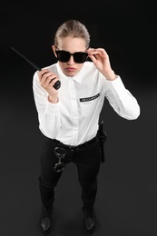 Photo of Female security guard using portable radio transmitter on dark background