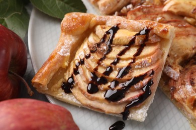 Piece of tasty apple pie with chocolate topping and fresh fruits on table, closeup