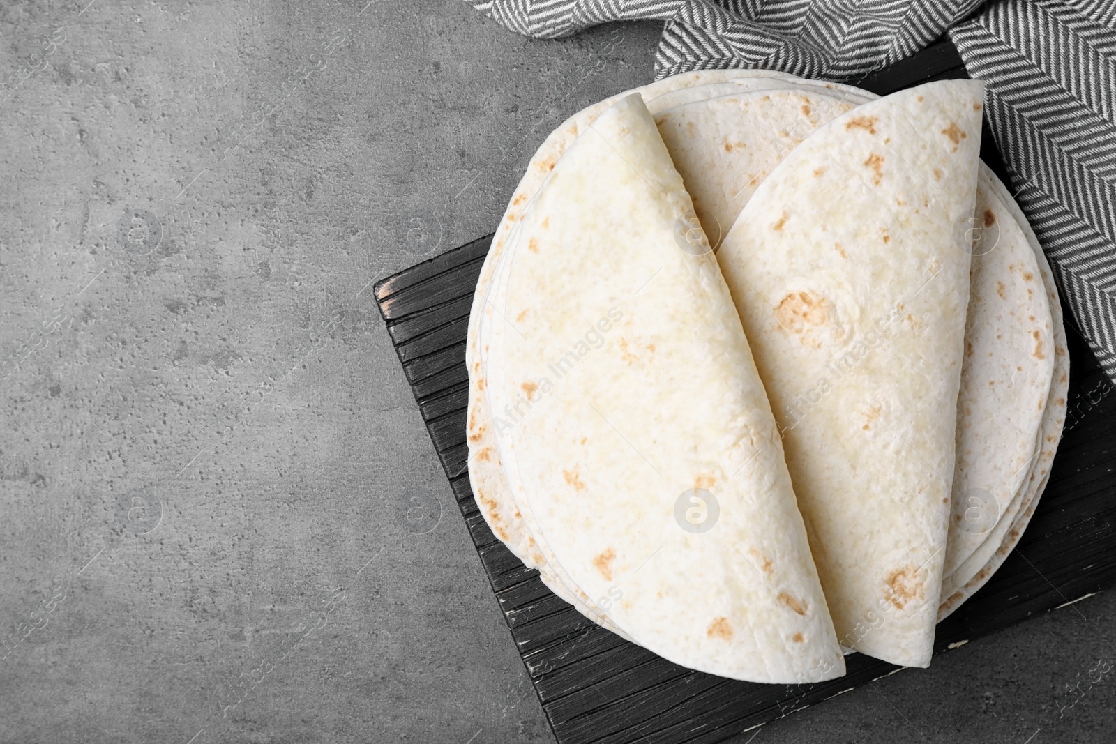 Photo of Corn tortillas on grey background, flat lay with space for text. Unleavened bread
