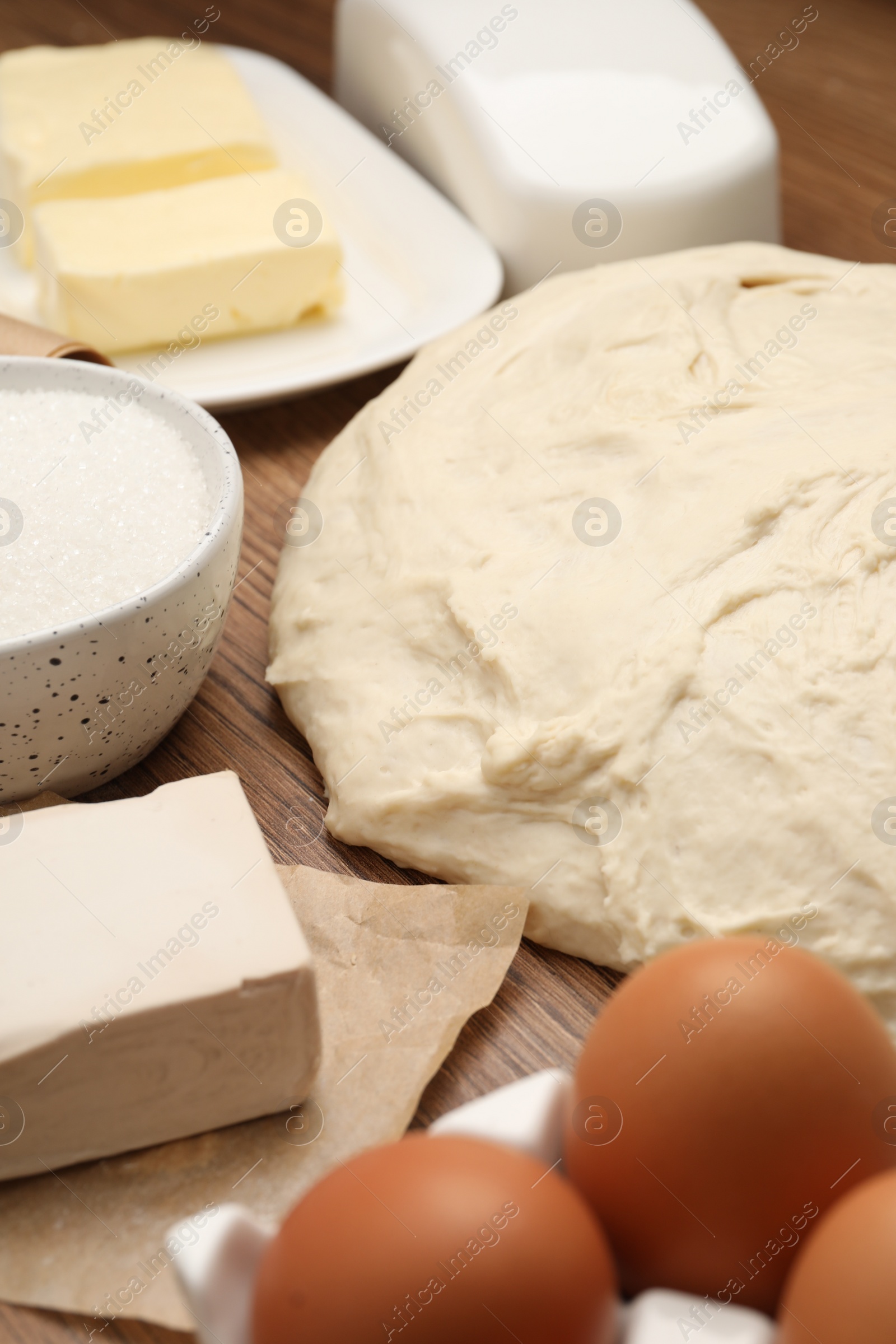 Photo of Fresh yeast dough and ingredients for cake on wooden table, closeup