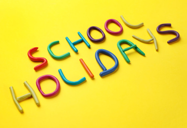 Phrase School Holidays made of modeling clay on yellow background