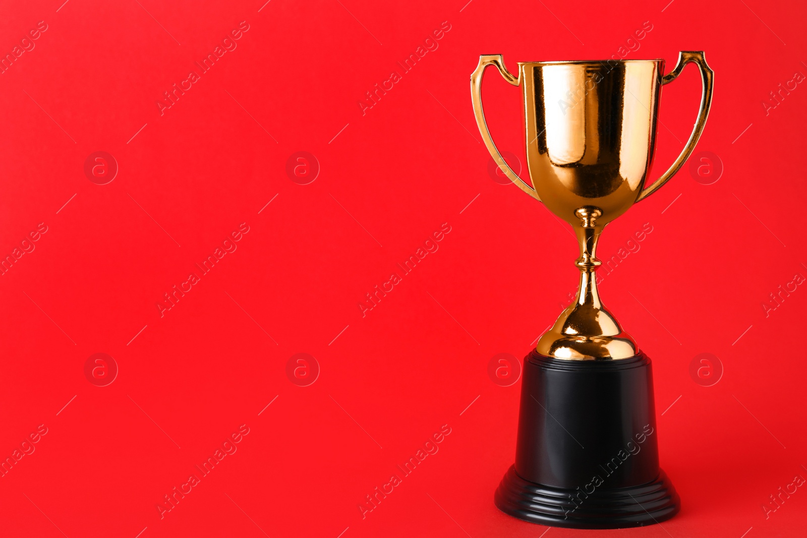 Photo of Golden trophy cup on red background. Space for text