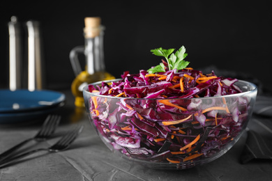 Photo of Bowl with fresh red cabbage salad on grey kitchen table