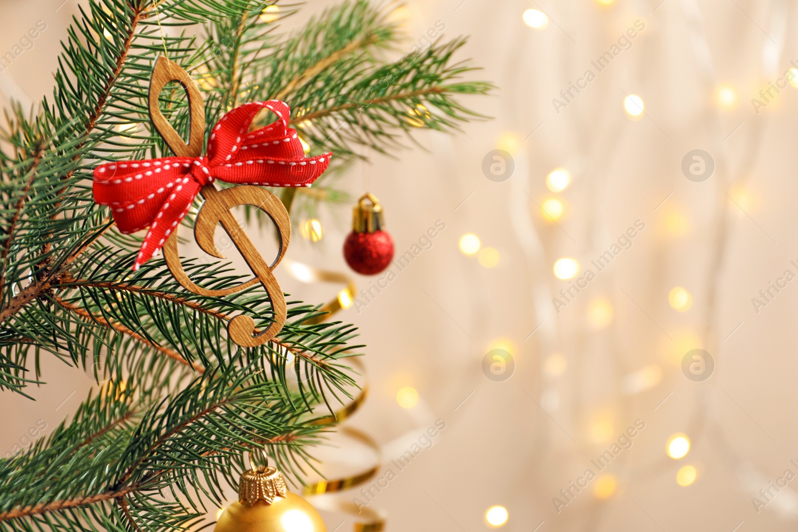 Photo of Fir tree branch with wooden treble clef on blurred background. Christmas music concept