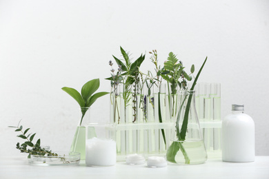 Photo of Herbal cosmetic products, laboratory glassware and ingredients on white table