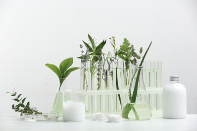 Herbal cosmetic products, laboratory glassware and ingredients on white table