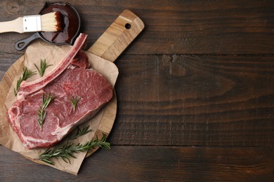 Photo of Raw meat, rosemary and marinade on wooden table, flat lay. Space for text
