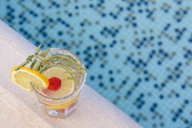Photo of Delicious refreshing lemonade with raspberries near swimming pool, above view. Space for text