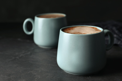 Photo of Cups of delicious hot cocoa on grey table. Space for text