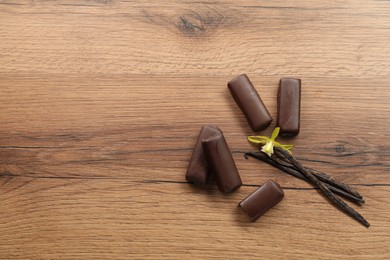 Glazed curd cheese bars, vanilla pods and flower on wooden table, flat lay. Space for text