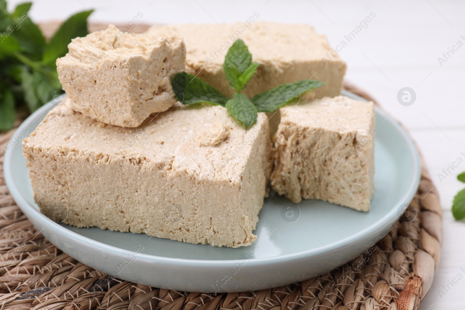 Photo of Pieces of tasty halva and mint on table, closeup