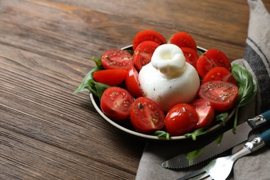 Photo of Delicious burrata cheese with tomatoes and basil served on wooden table. Space for text