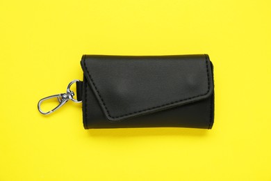 Photo of Stylish leather keys holder on yellow background, top view