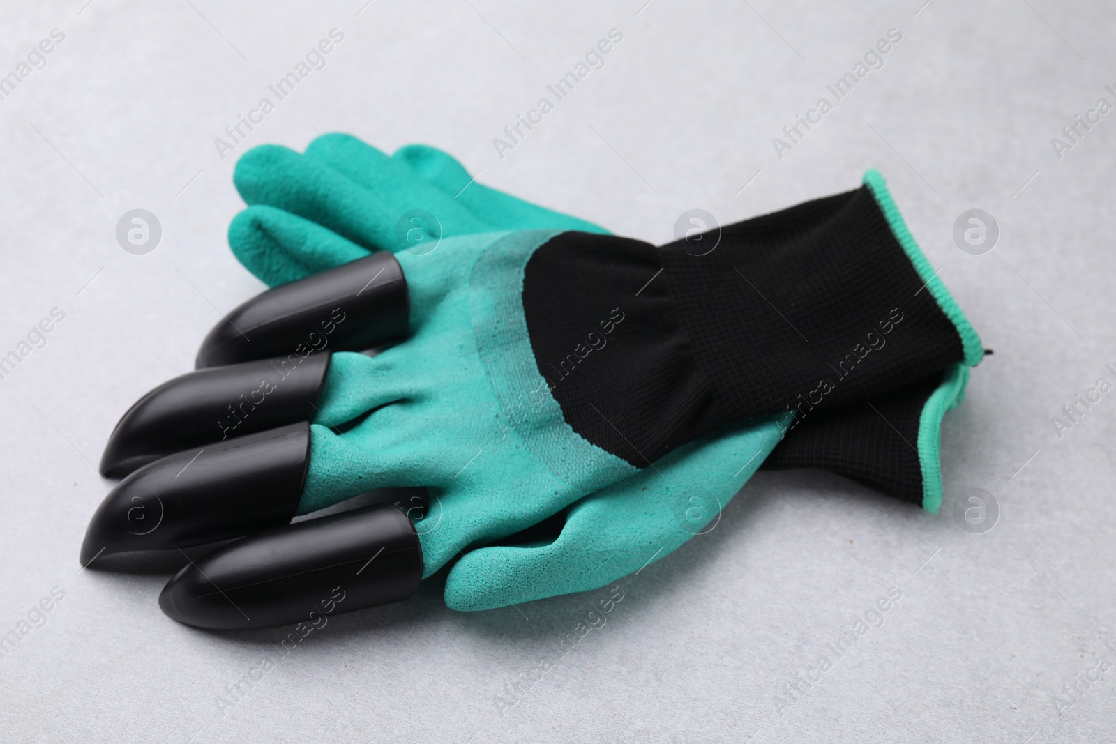 Photo of Pair of claw gardening gloves on light grey table, closeup