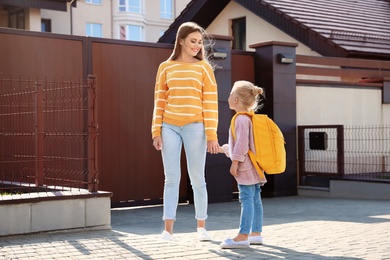 Young mother taking her little child to school on street