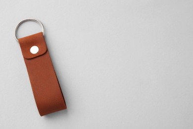 Leather keychain with Ukrainian coat of arms on light grey background, top view. Space for text