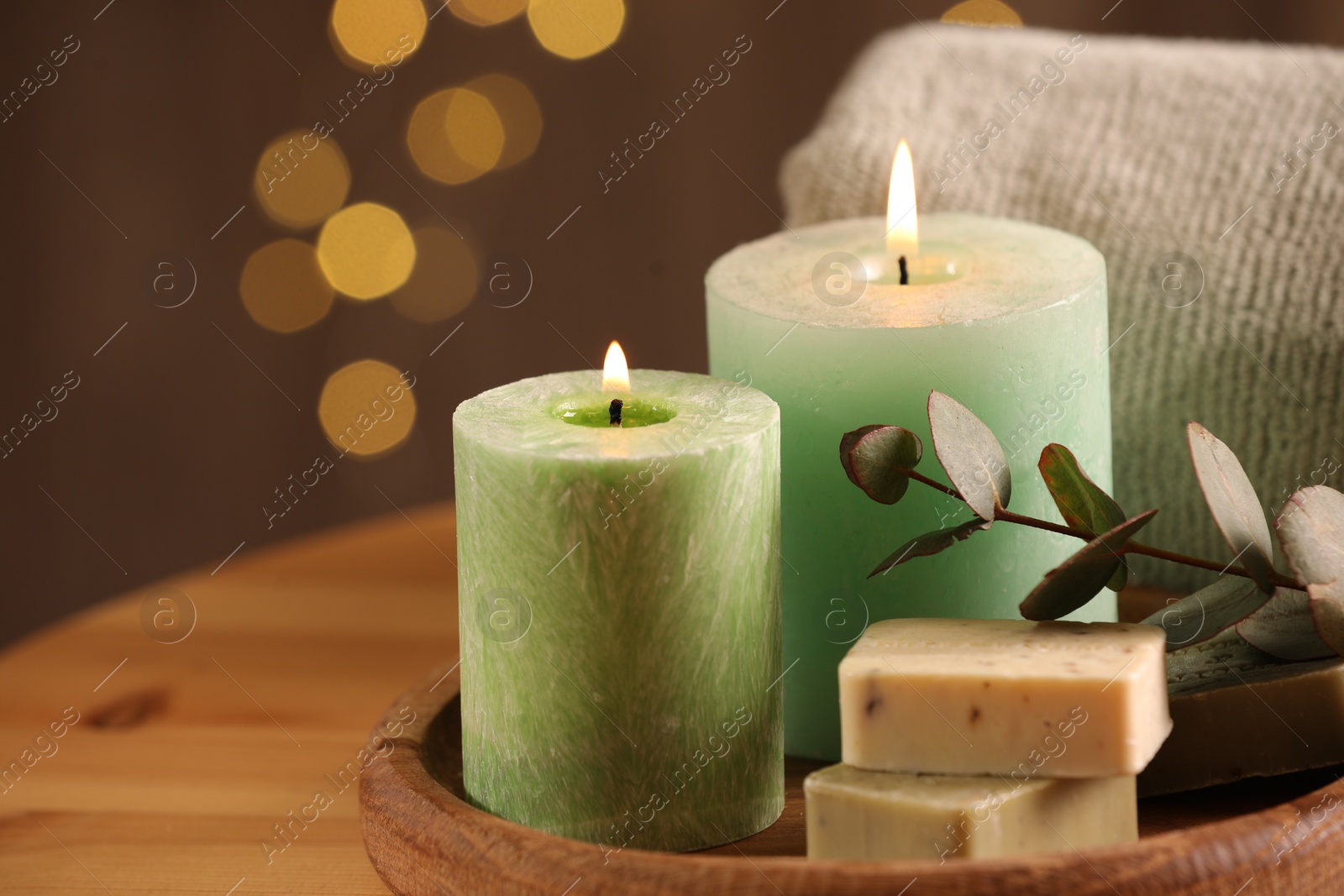 Photo of Spa composition. Burning candles, soap, towel and eucalyptus branch on wooden table, space for text