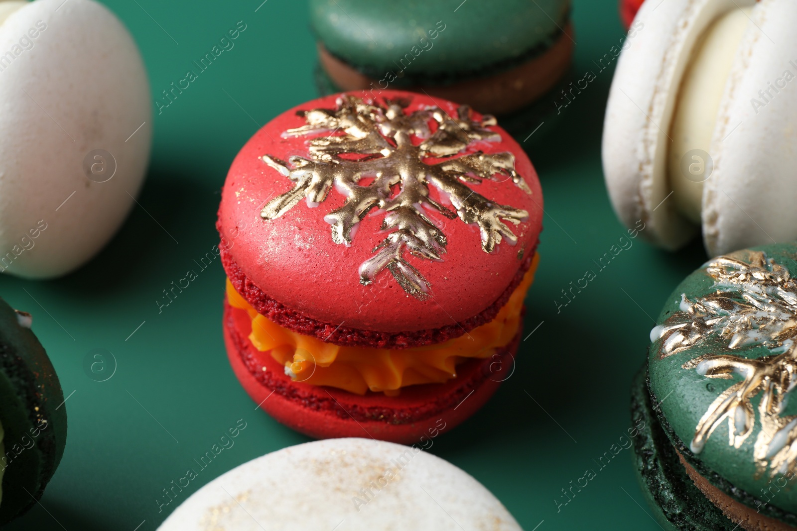 Photo of Beautifully decorated Christmas macarons on green background, closeup