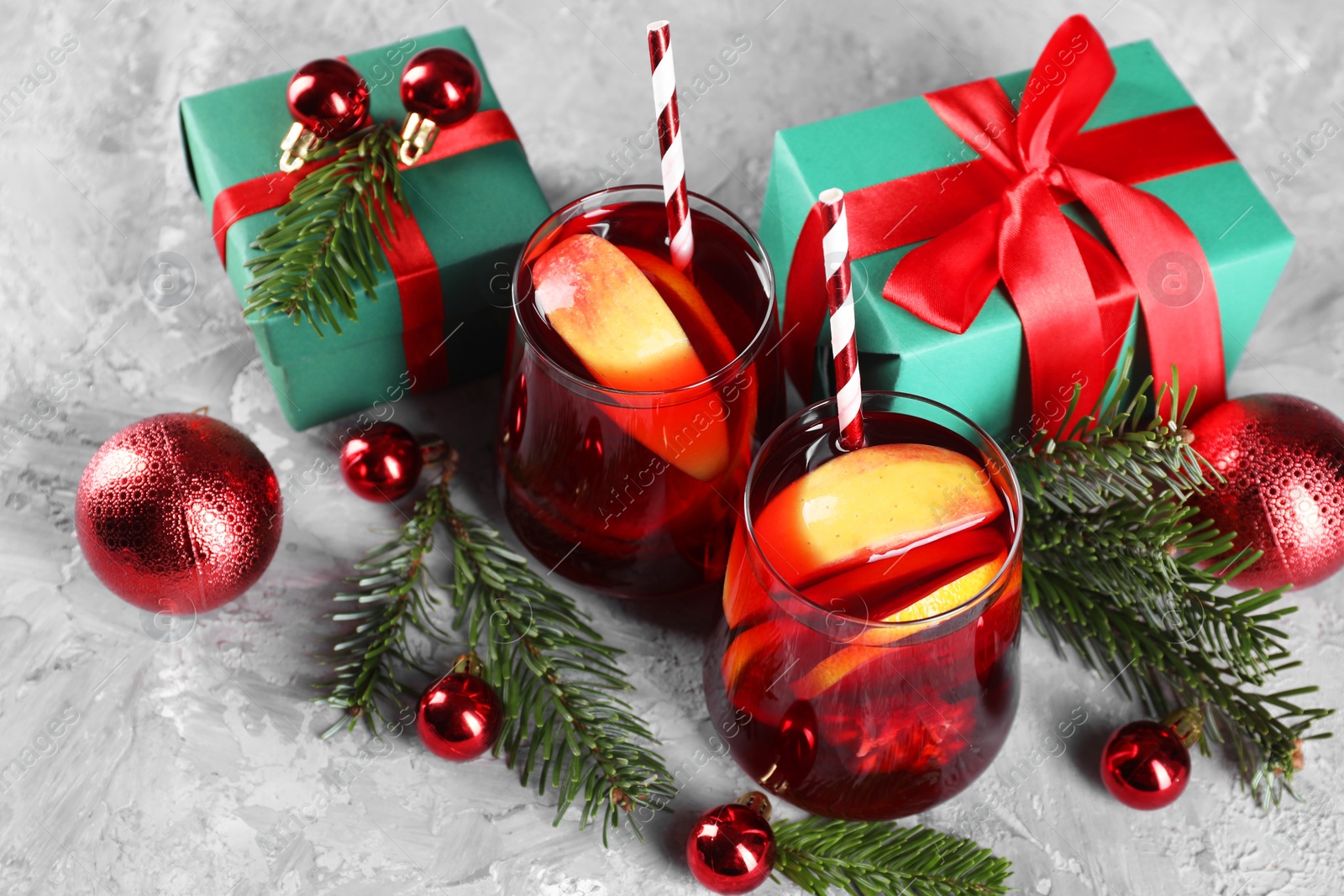 Photo of Delicious Sangria drink in glasses and Christmas decorations on grey textured table, above view