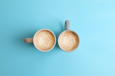 Cups of coffee on blue background, top view